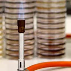 A lit Bunsen burner sits in front of stacks of Petri dishes.