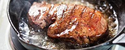 A steak frying in a pan.