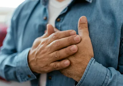 A man holding his chest, suggesting heart failure.