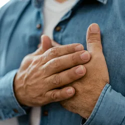 A man holding his chest, suggesting heart failure.