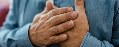 A man holding his chest, suggesting heart failure.
