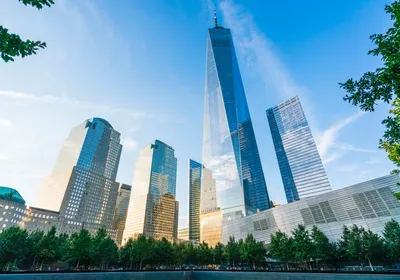 One World Trade Center is seen at sunset with the 9/11 memorial in the foreground.