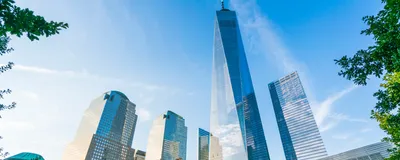 One World Trade Center is seen at sunset with the 9/11 memorial in the foreground.