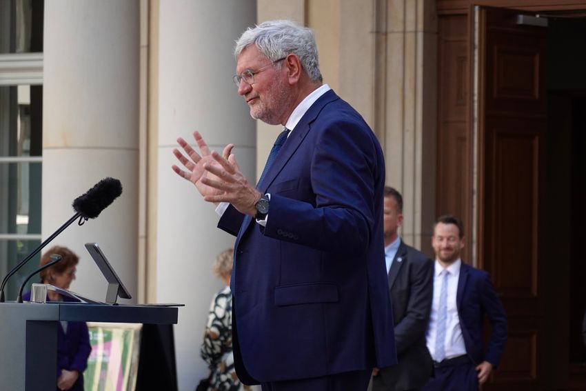 A man smiles gives a speech on a podium,