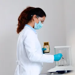 A scientist weighing a powdered reagent on an analytical balance