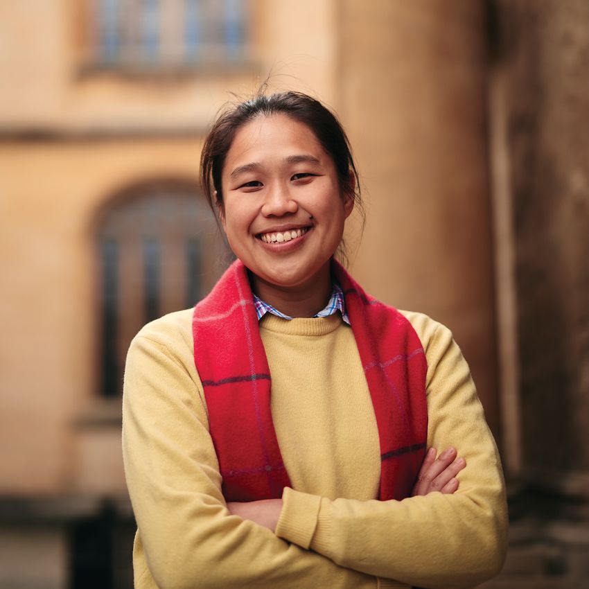 Chloe Yap wears a yellow sweater and red scarf in a photo taken outside.