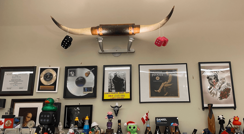Image of steer horns mounted on the wall. Below, there are various frames related to country music. Image of steer horns mounted on the wall. Below, there are various frames related to country music.