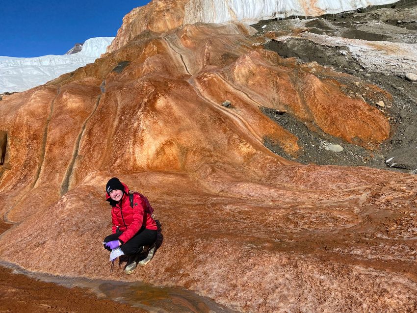 Angela Zoumplis kneels down to collect a sample at Blood Falls in Antarctica.