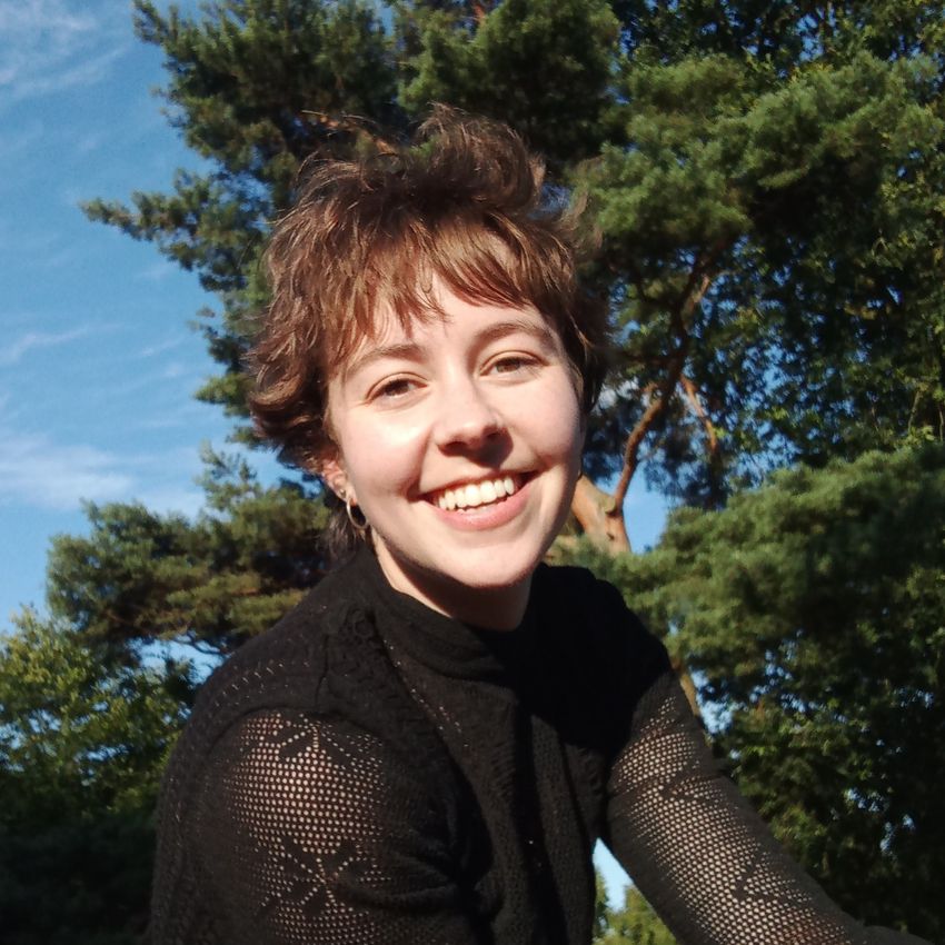 A photograph of Luísa Amado against a natural background wearing a black top. A photograph of Luísa Amado against a natural background wearing a black top.