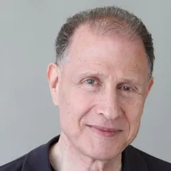 Gad Gilad wears a dark shirt against a light background in a headshot.