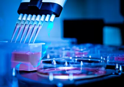 A robotic face, representing an AI scientist, is overlayed under an image of a multi-pipet taking up red liquid in a molecular biology wet lab that is bathed in blue light.