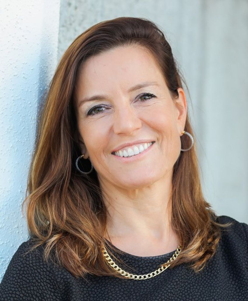 Pamela Tenaerts wears a dark shirt and a gold necklace in a headshot photo against a white background. Pamela Tenaerts wears a dark shirt and a gold necklace in a headshot photo against a white background.