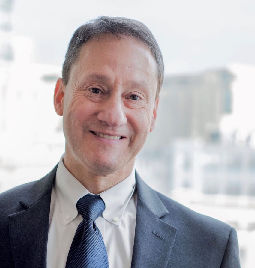 Ken Getz wears a dark blue suit and blue tie in a headshot photo taken outdoors. Ken Getz wears a dark blue suit and blue tie in a headshot photo taken outdoors.