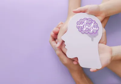 Hands holding a brain paper cutout.